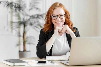 eine Frau sitzt an einem Schreibtisch mit ihrem Laptop