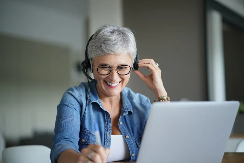 eine Frau mit Kopfhörern und mit einem Laptop