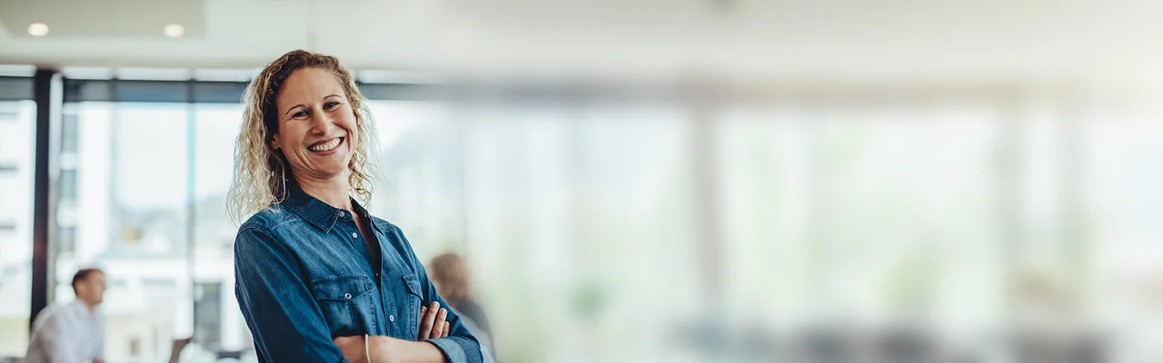 eine Frau, die mit verschränkten Armen in einem Büro steht