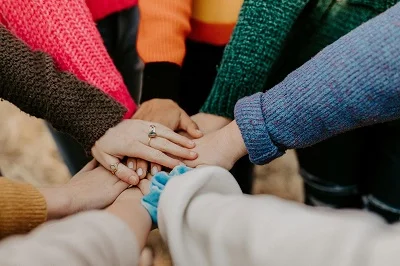 eine Gruppe von Menschen, die in einem Kreis Hände halten