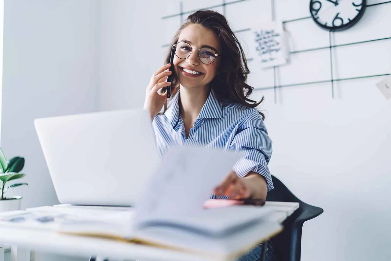 eine Frau, die an ihrem Schreibtisch sitzt und am Telefon spricht