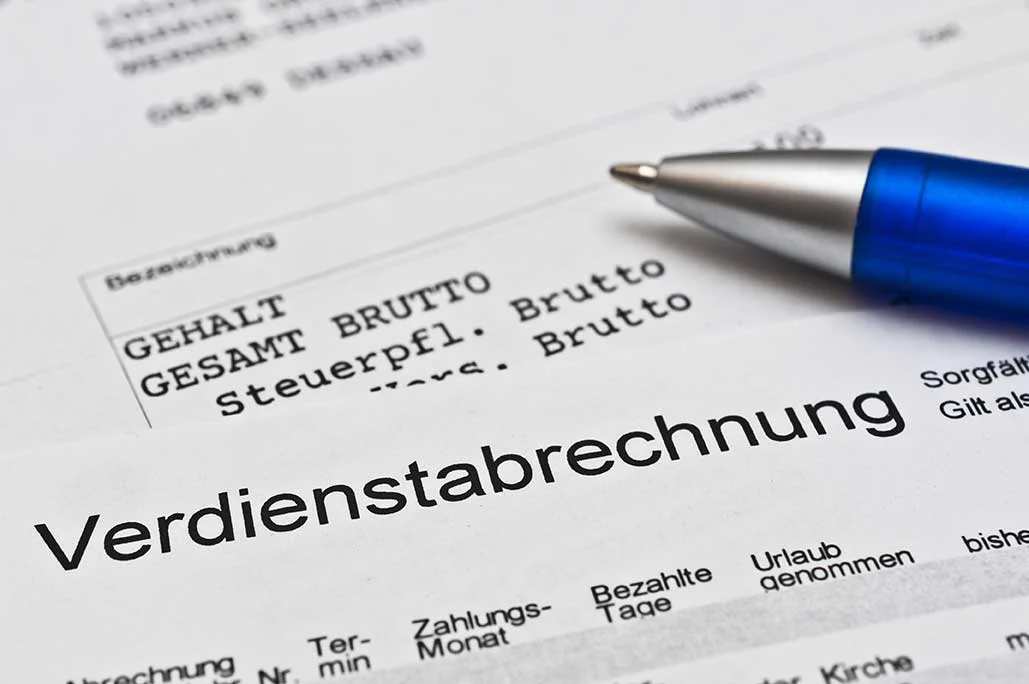 einen Stift auf einem Papier mit dem Wort "Verdienstabrechnung"