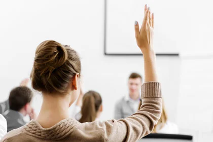 eine Frau, die ihre Hand in einem Klassenzimmer hebt