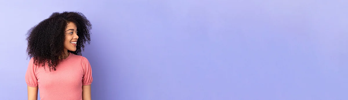 eine Frau, die mit den Händen an den Hüften an einer Wand steht